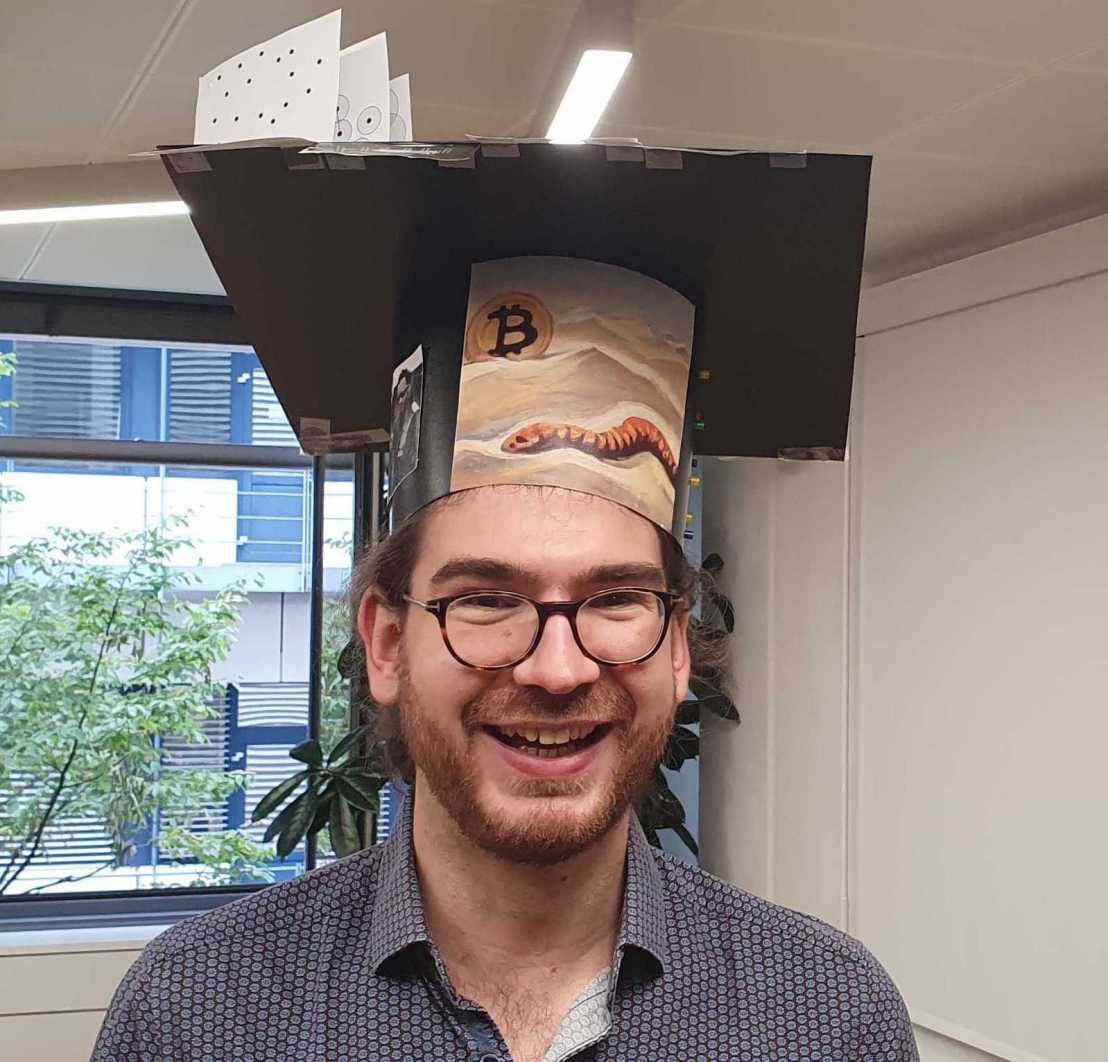 Portrait picture of Max Horn with PhD hat crafted by lab mates
